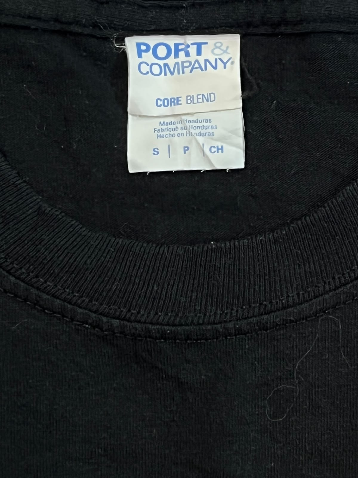 Close-up of a black crewneck t-shirt showing the inner neck label which reads 'PORT & COMPANY CORE BLEND'.