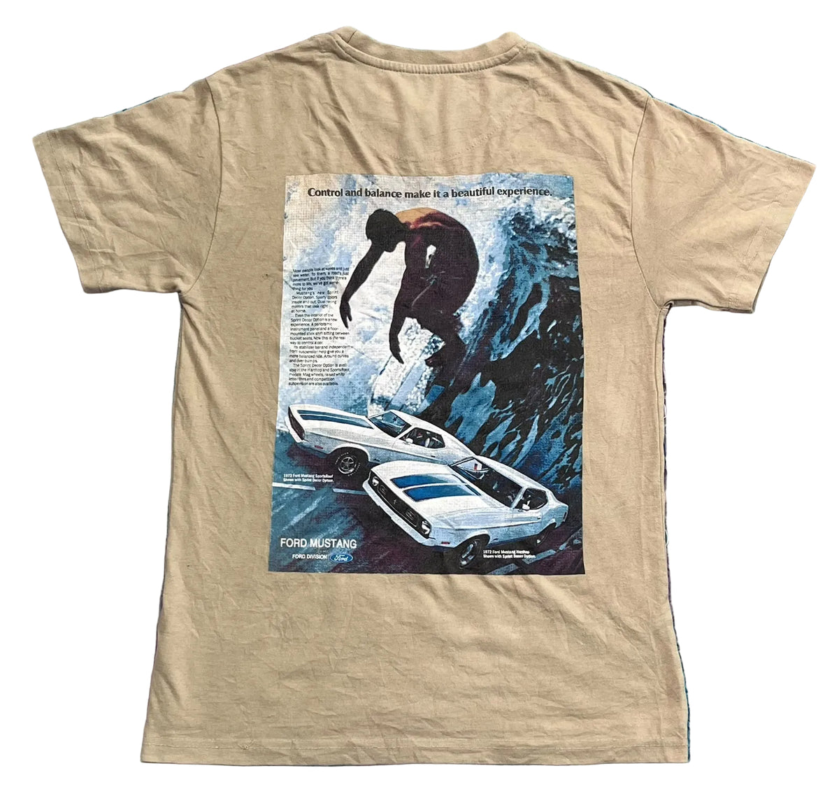 A beige graphic t-shirt  The back of the shirt features a large vintage-style print of a white Ford Mustang car with blue racing stripes, a driver jumping over a cliff, and a blue wave, with 'Ford Mustang' text at the bottom.