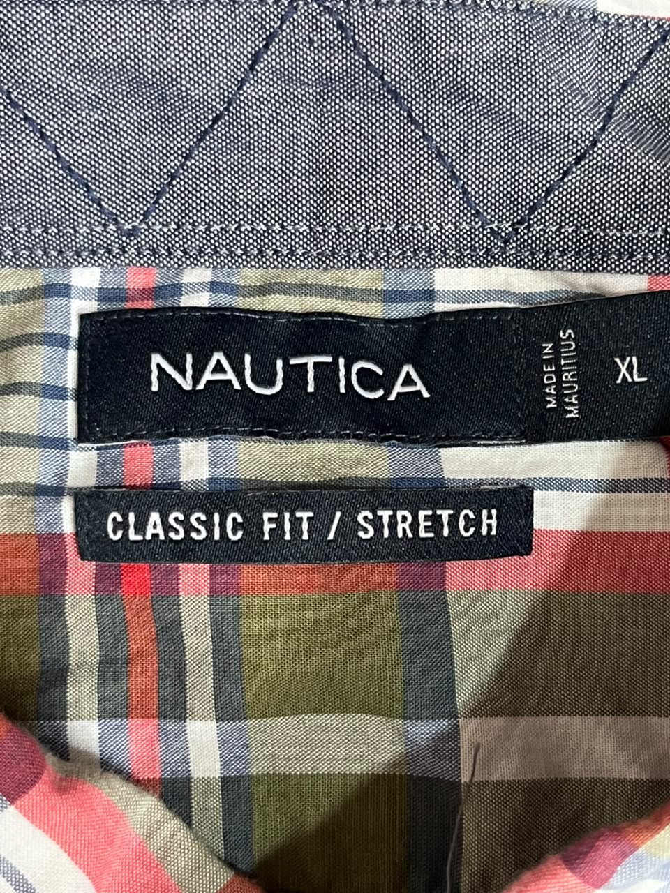Close-up of a Nautica plaid shirt lining with a black size label reading 'NAUTICA', 'CLASSIC FIT / STRETCH', and 'XL'.