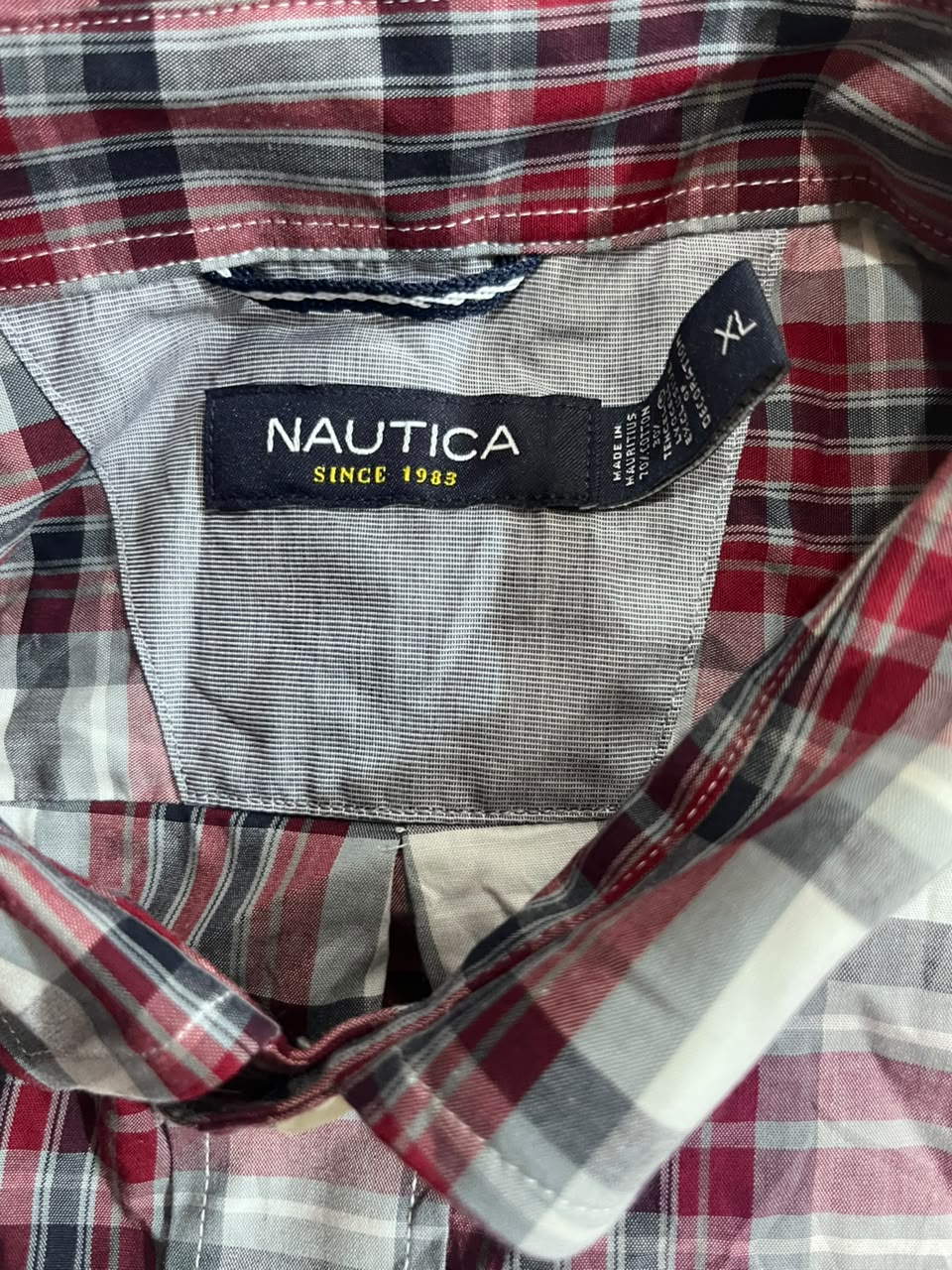 Close-up of a Nautica plaid shirt collar showing the brand label and size XL.