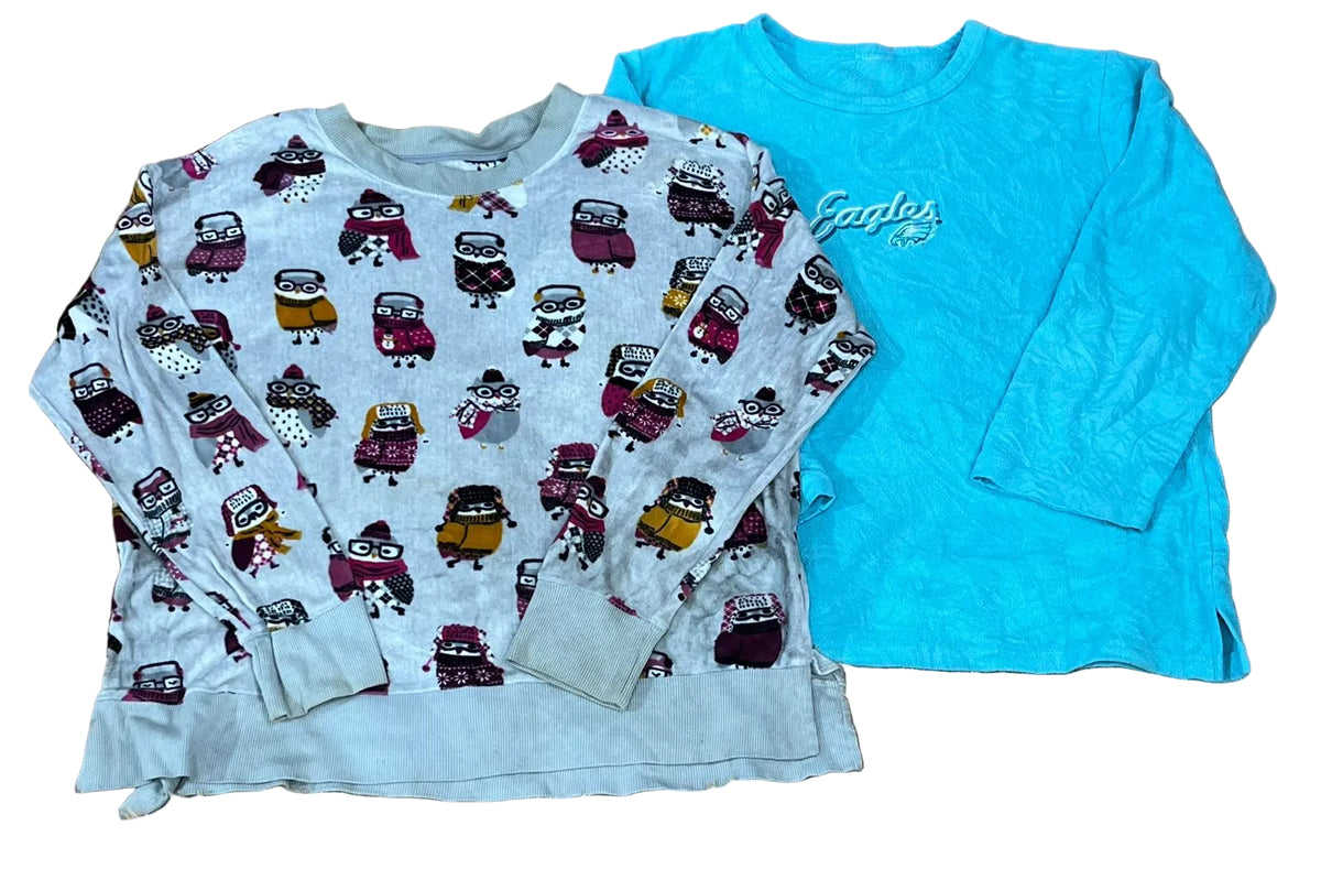 Two long-sleeve children's tops one light gray sweatshirt with an allover cartoon character print, and one bright turquoise long-sleeve top with 'Cactus' printed across the chest.