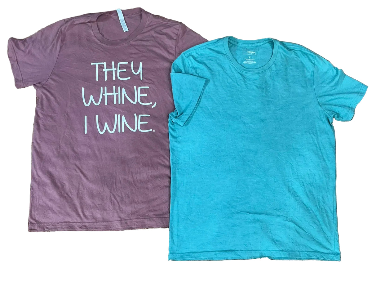 Two short-sleeve crewneck t-shirts The left shirt is heathered mauve with white text reading 'THEY WHINE, I WINE.