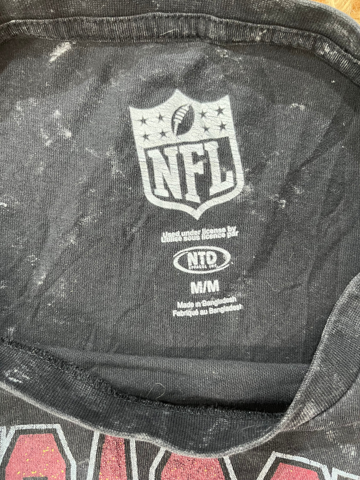 Close-up of the inside collar of a black NFL t-shirt, showing the white NFL shield logo, NTD licensing mark, and 'M/M' size label.