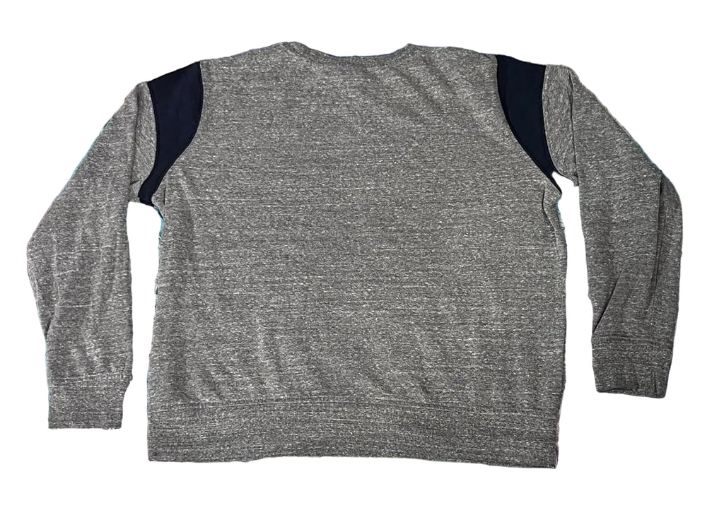 A heather gray long-sleeve top with contrasting dark navy shoulder panels, laid flat on a pastel purple, blue, and pink shaggy rug.