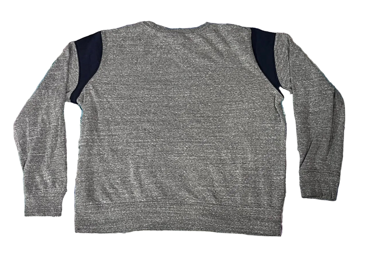 A heather gray long-sleeve top with contrasting dark navy shoulder panels, laid flat on a pastel purple, blue, and pink shaggy rug.