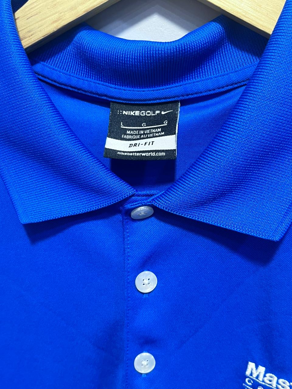 Close-up of a blue Nike Golf polo shirt with a tag on a hanger.