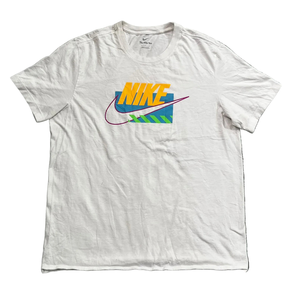 A white short-sleeve Nike t-shirt, featuring a colorful retro graphic on the chest with the word 'NIKE' in orange and yellow, a blue swoosh, and green and pink accents.