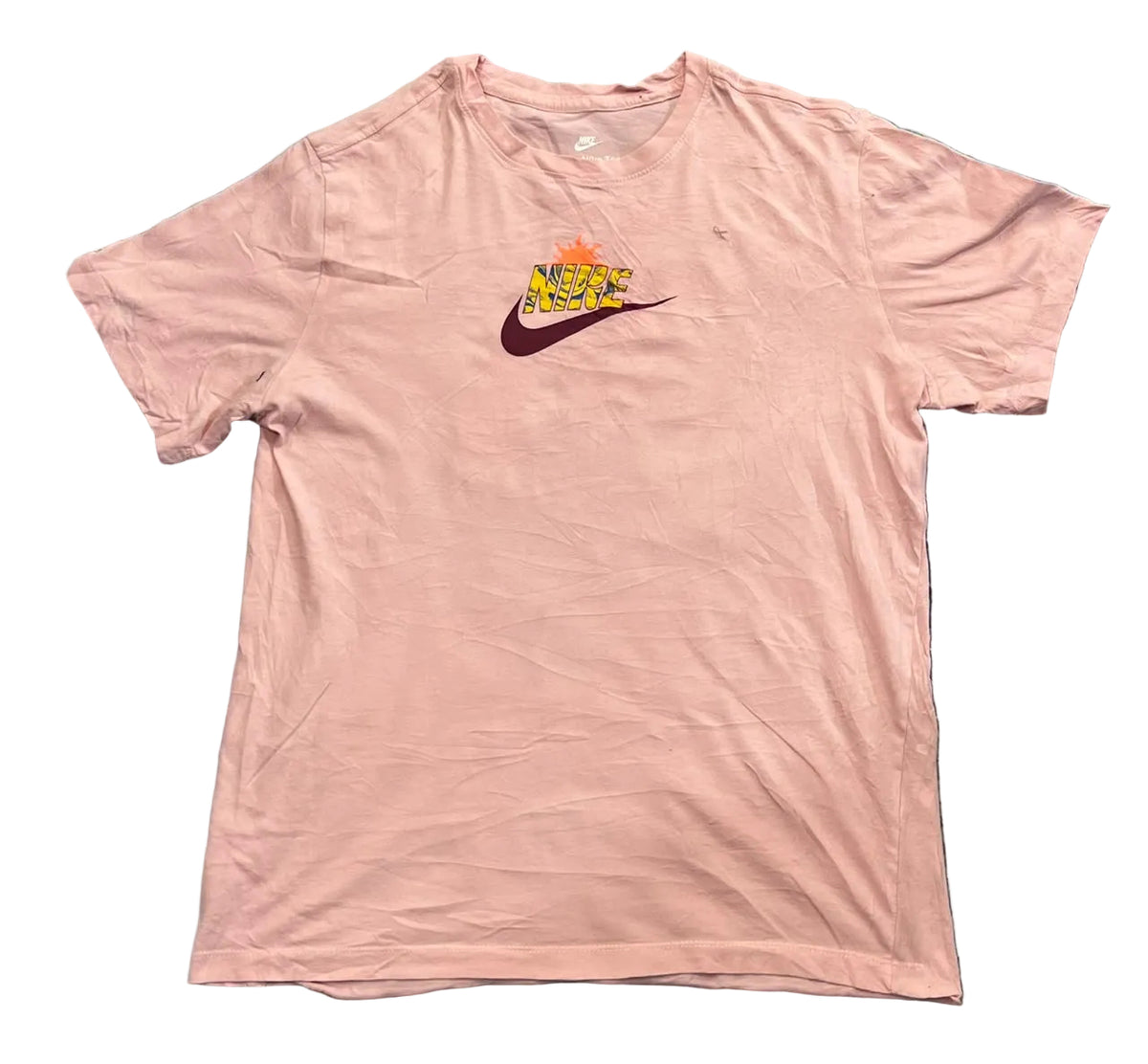 A light pink short-sleeve Nike t-shirt . The shirt features a small graphic on the left chest with a yellow and orange Nike logo and a dark purple swoosh.