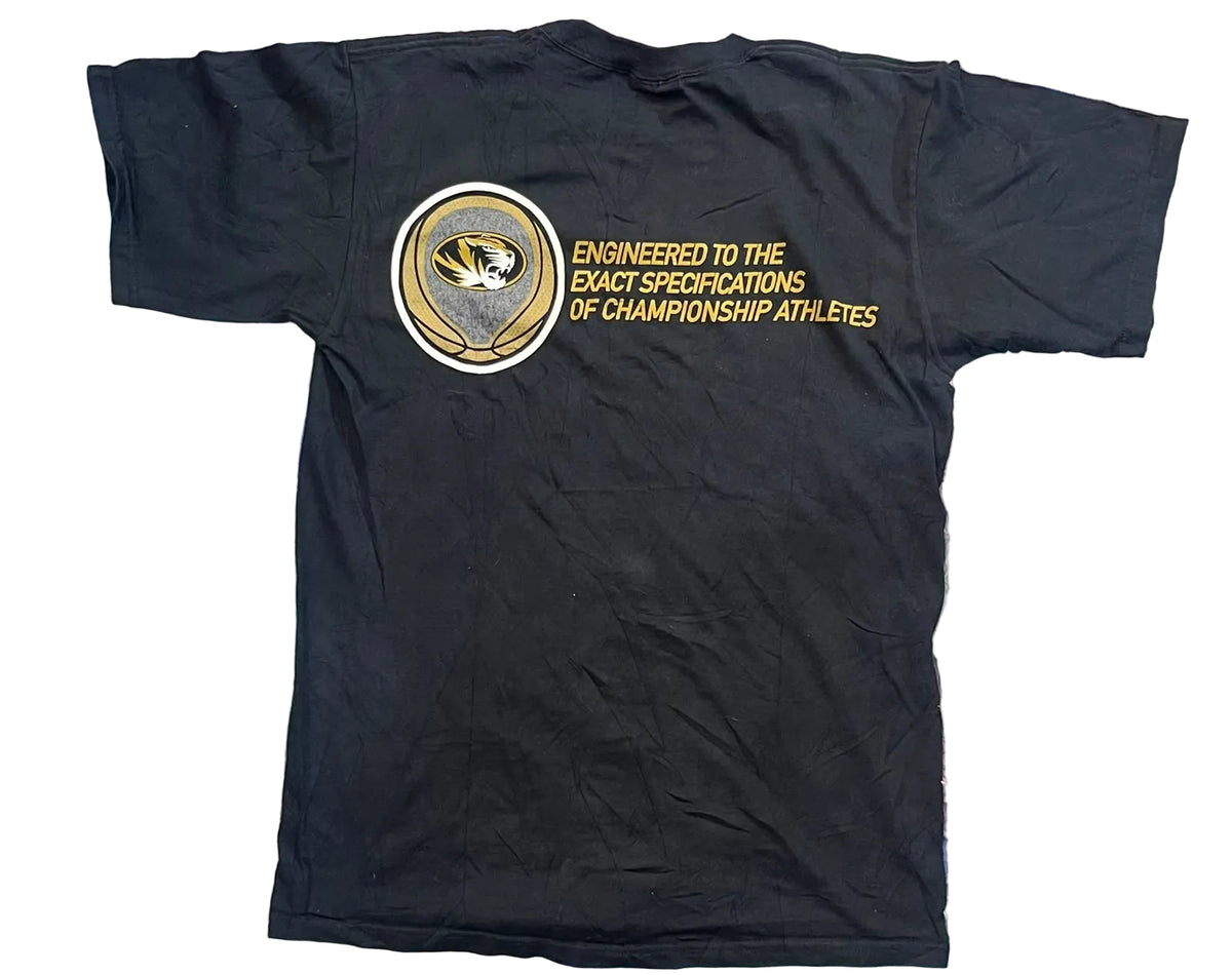 A black short-sleeve t-shirt. The back of the shirt features a circular gold, white, and black graphic with the text 'ENGINEERED TO THE EXACT SPECIFICATIONS OF CHAMPIONSHIP ATHLETES'.