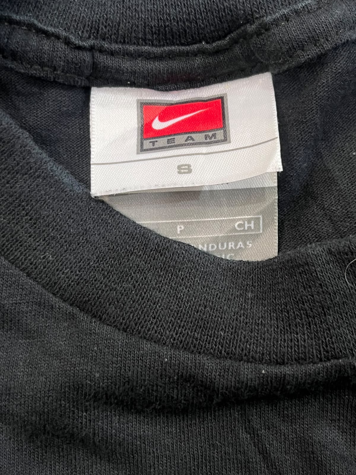 Close-up of the inside collar of a black Nike shirt, showing the white Nike Team size 8 tag.