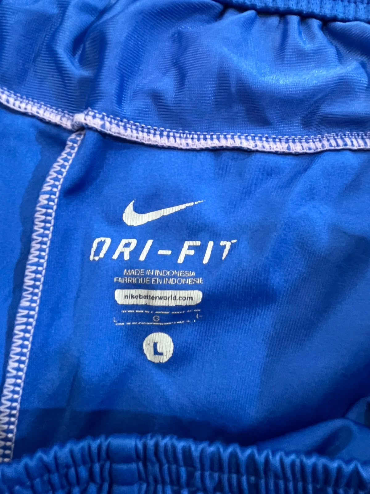 Close-up of a bright blue Nike Dri-FIT athletic garment showing the white Nike swoosh, DRI-FIT text, and size label.