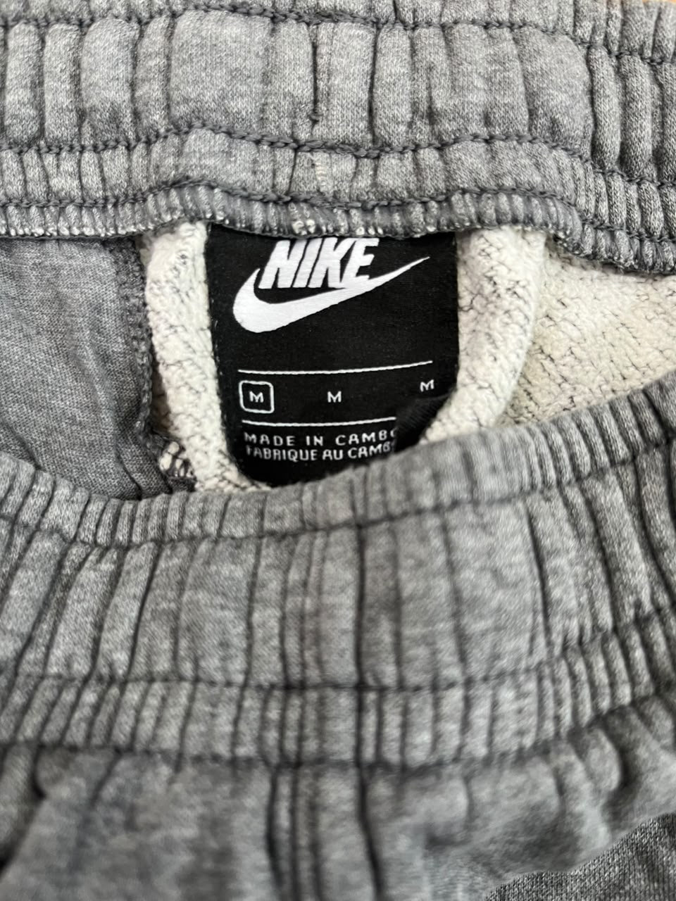 Close-up of a gray ribbed knit garment showing the interior neck label with a black Nike swoosh and white text.