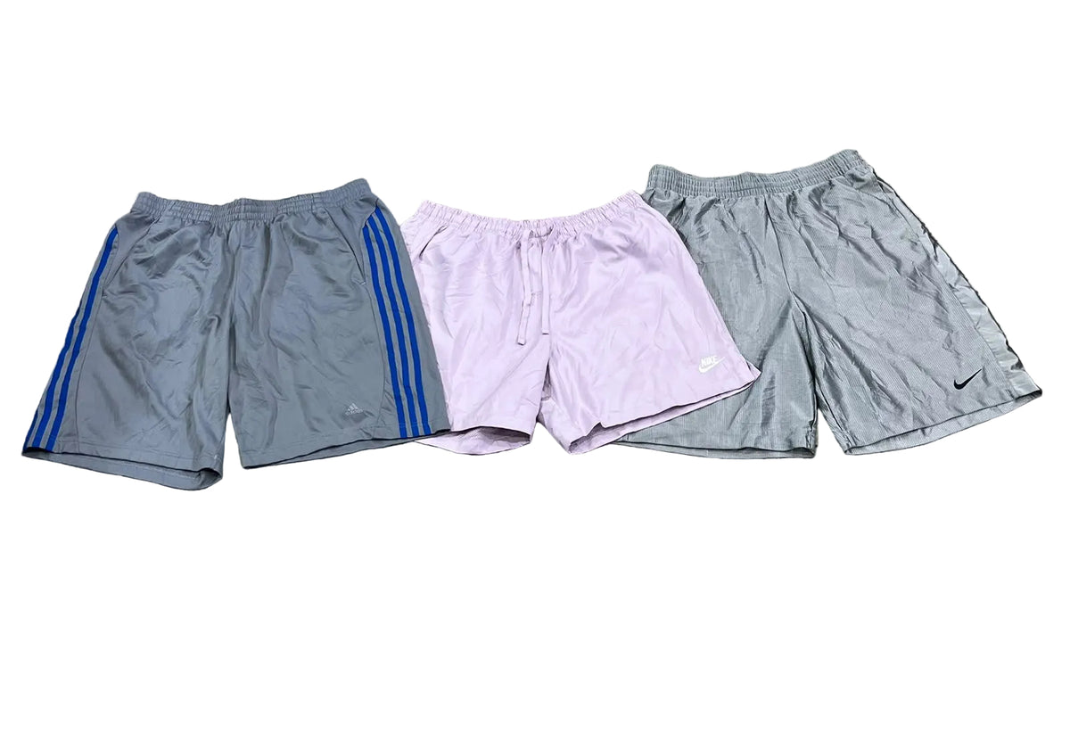 Three pairs of athletic shorts gray shorts with blue side stripes on the left, light lavender drawstring shorts in the center, and gray Nike shorts on the right.