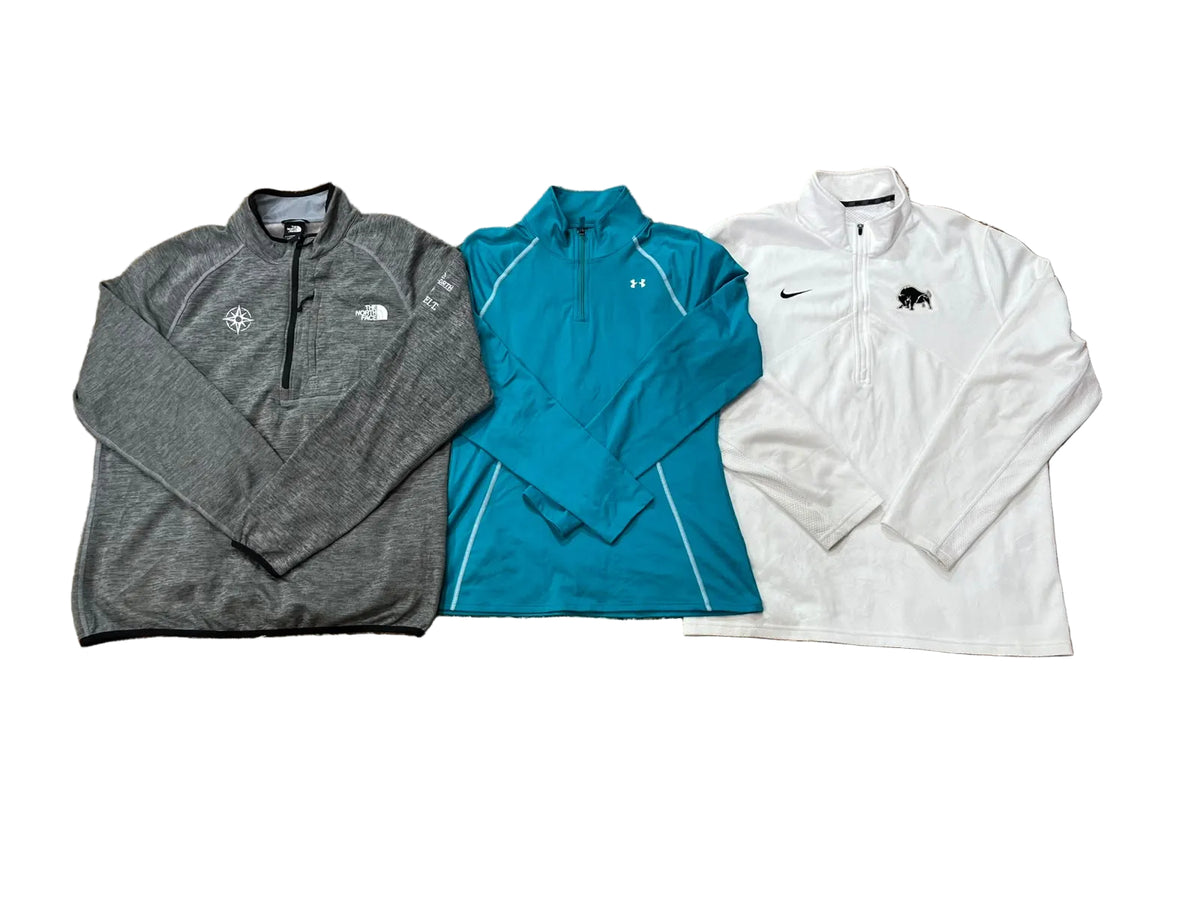 Three athletic quarter-zip jackets: a heather gray The North Face pullover, a teal Under Armour pullover, and a white Nike pullover.