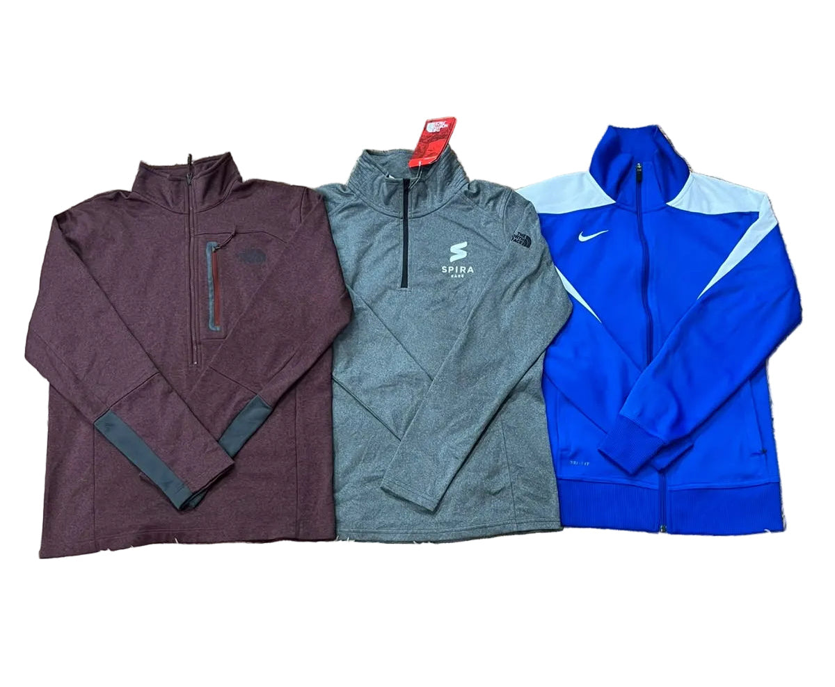 Three athletic quarter-zip jackets: a burgundy one on the left, a gray one in the center with a visible Puma logo, and a bright blue one on the right with a white Nike swoosh.