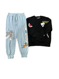 A pair of light blue Tom and Jerry sweatpants and a black crewneck sweatshirt with graphic patches,