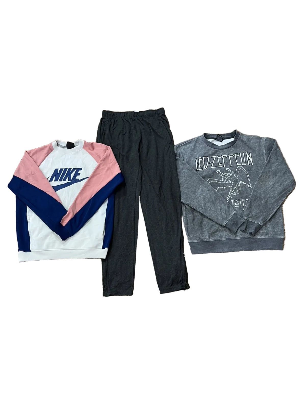 Three clothing items: a Nike colorblock sweatshirt in white, pink, and navy; a pair of black jogger pants; and a gray Led Zeppelin graphic sweatshirt. Bare feet are visible at the bottom edge.
