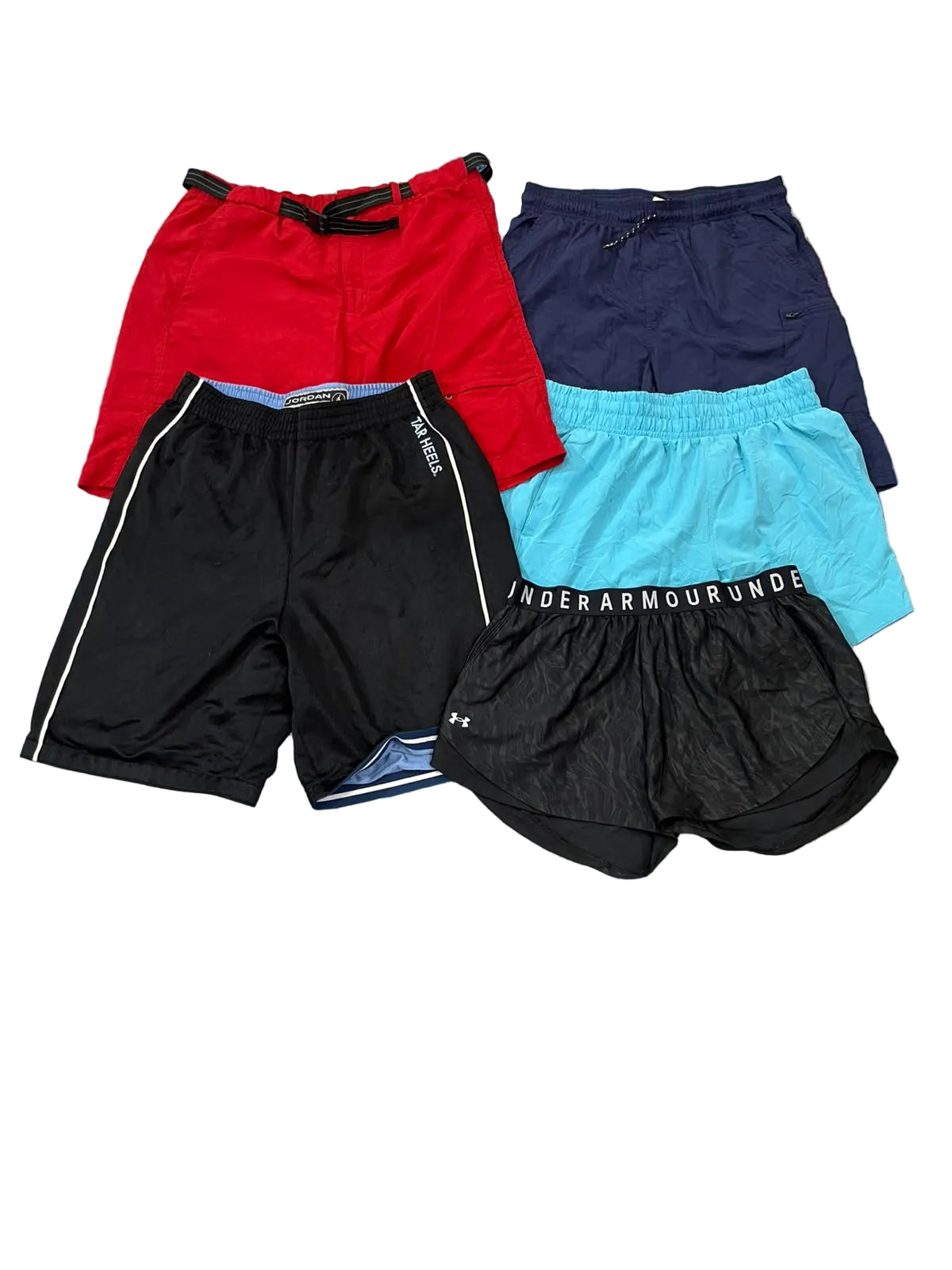 Four pairs of athletic shorts in red, navy, black, and light blue, . Under Armour branding is visible on the waistbands.