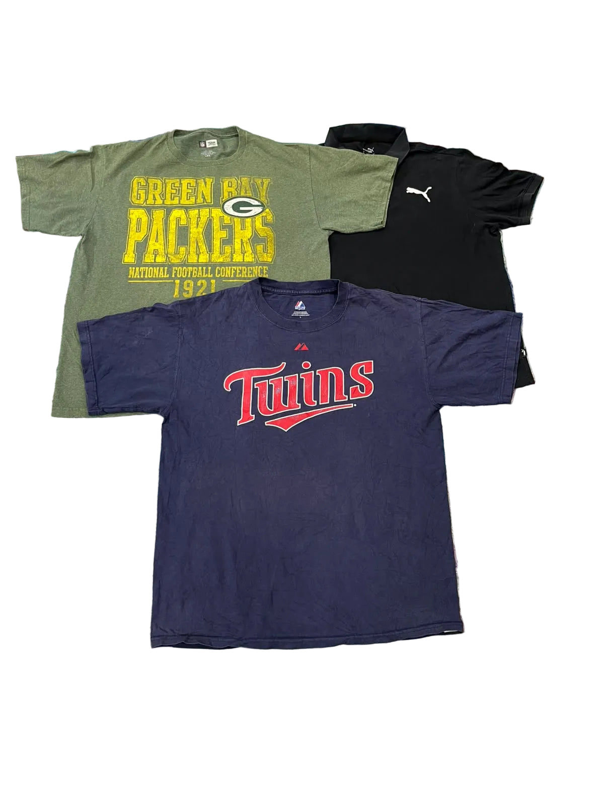 Three athletic t-shirts a green Green Bay Packers graphic tee, a black Puma polo, and a navy blue Minnesota Twins t-shirt.