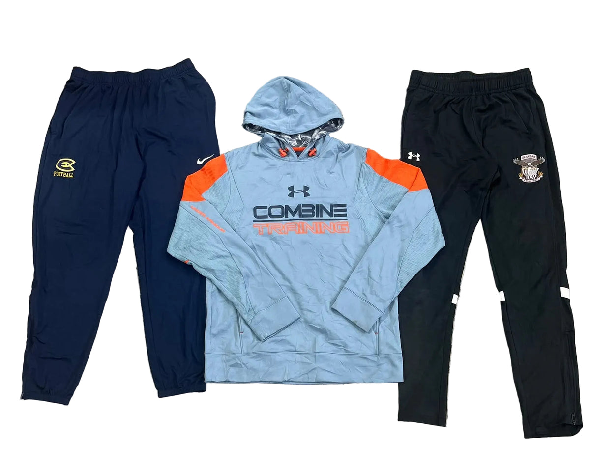 Three athletic apparel items: navy jogger pants with a yellow logo on the left, a light blue Under Armour hooded sweatshirt with orange panels and 'COMBINE' text in the center, and black jogger pants with a crest on the right.