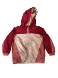 A children's hooded jacket The jacket has a dark red upper section and sleeves, a light beige front panel, and coral-pink side panels.