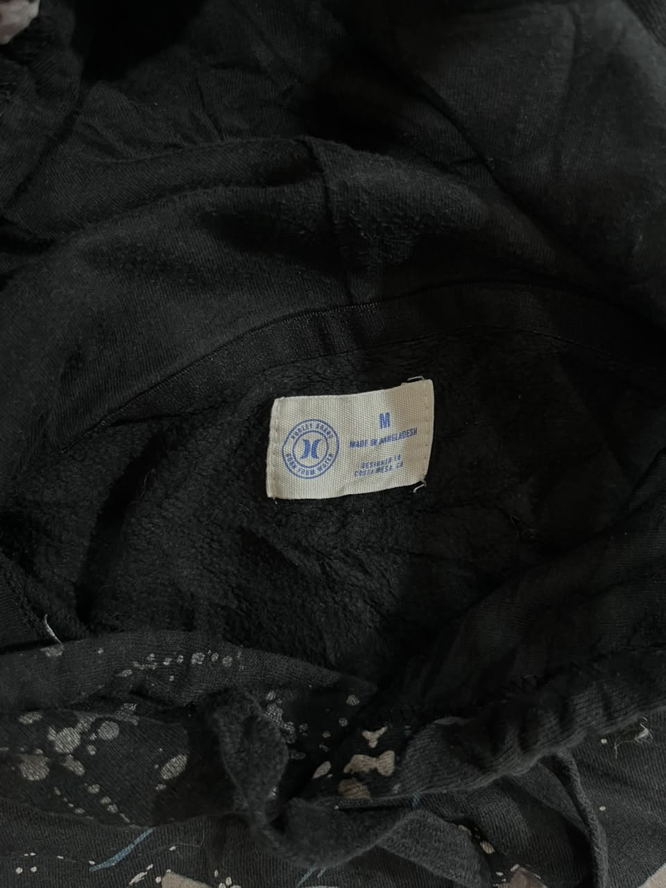 Close-up of a black plush fleece garment interior showing a sewn-on size and brand label that reads 'Herkules Outfitters' and 'M'.