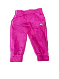 Bright pink Puma track pants with white side stripes and a white Puma logo,