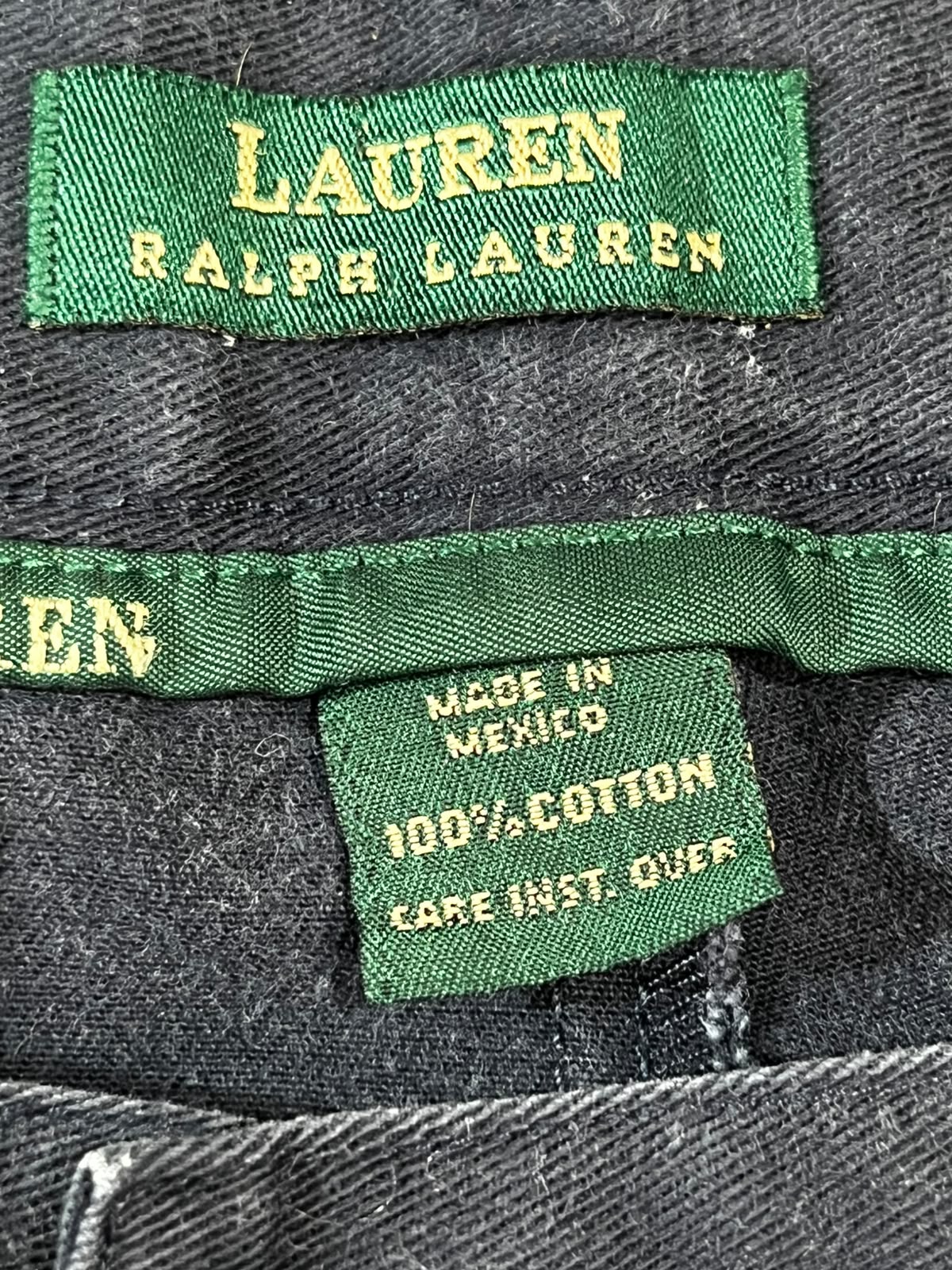 Close-up of a dark gray denim garment showing two green embroidered labels. The top label reads 'Lauren Ralph Lauren' in yellow, and the lower label reads 'EN' on the left and 'Made in Mexico, 100% Cotton, Care Inst.
