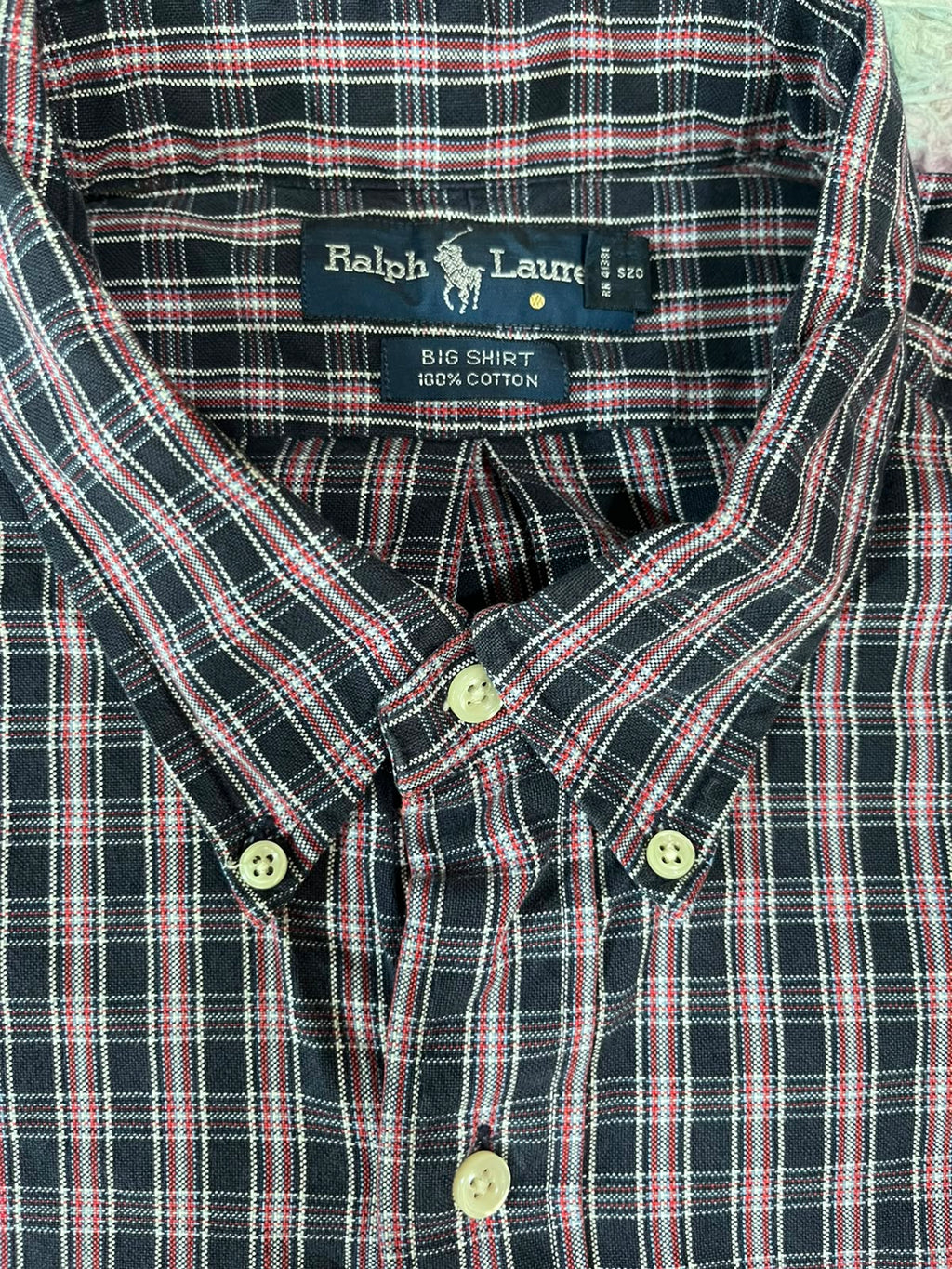 Close-up of a Ralph Lauren button-down shirt with a navy, red, and white plaid pattern, showing the inner neck label and front buttons.