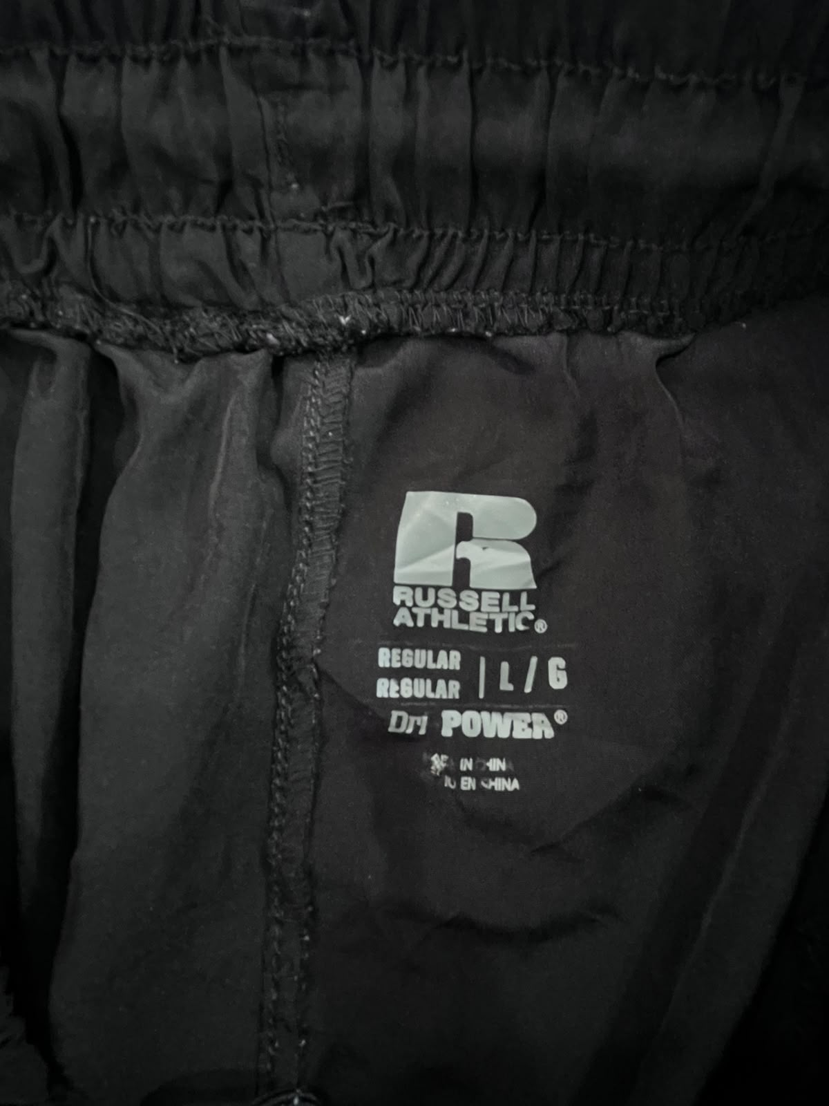 Close-up of black athletic pants showing the inner waistband and a visible Russell Athletic Dry Power label.
