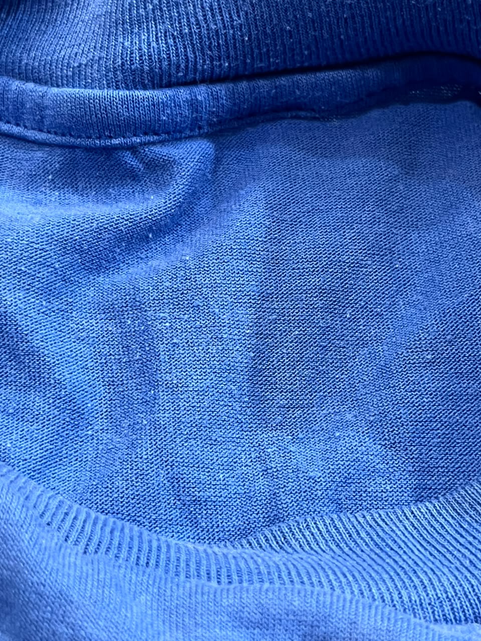 Close-up of a blue knit fabric with ribbed collar and hem details.