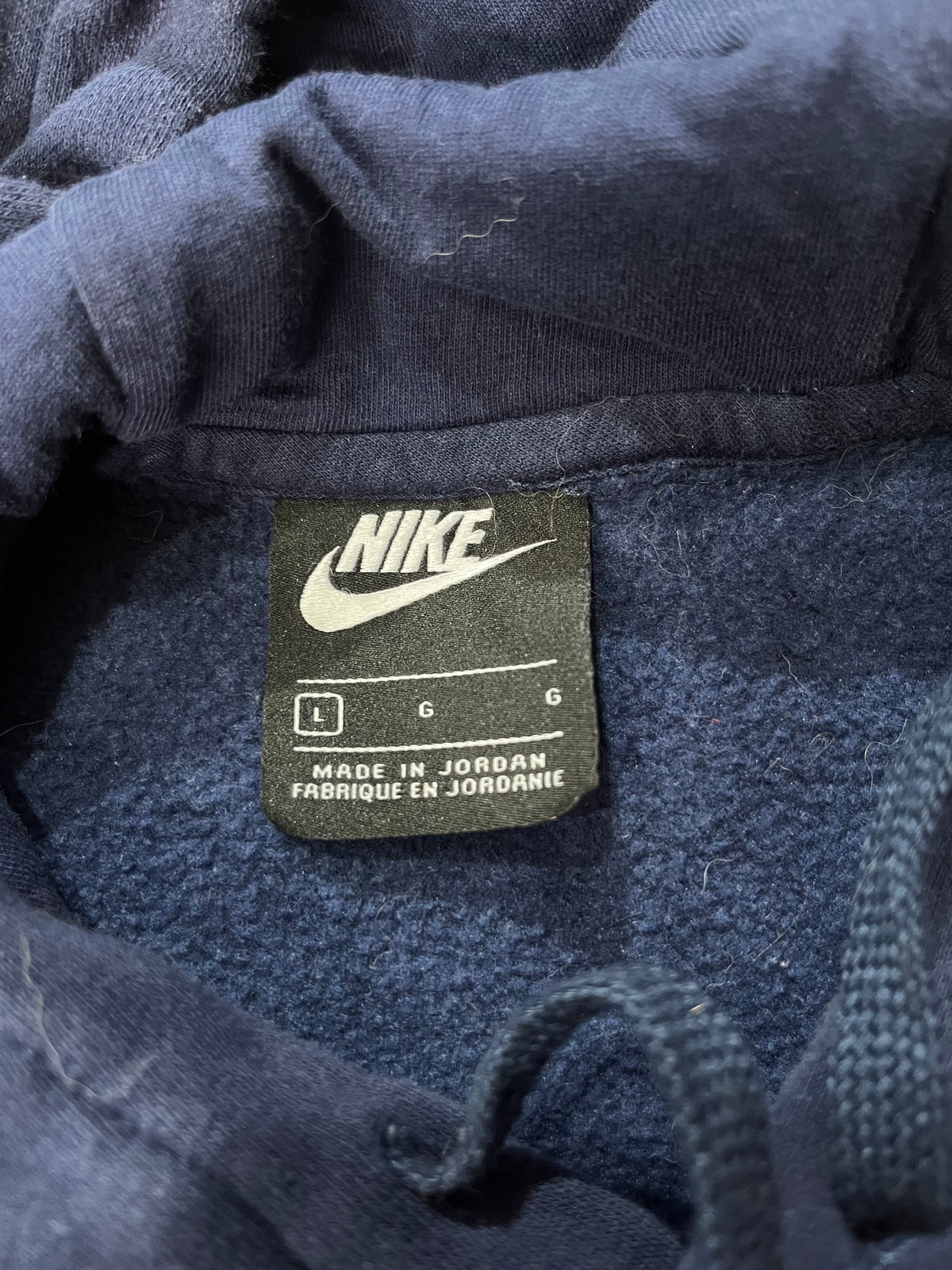 Close-up of a dark navy blue Nike garment, likely a hoodie, showing the interior hood lining and a black Nike brand tag with white text and logo.