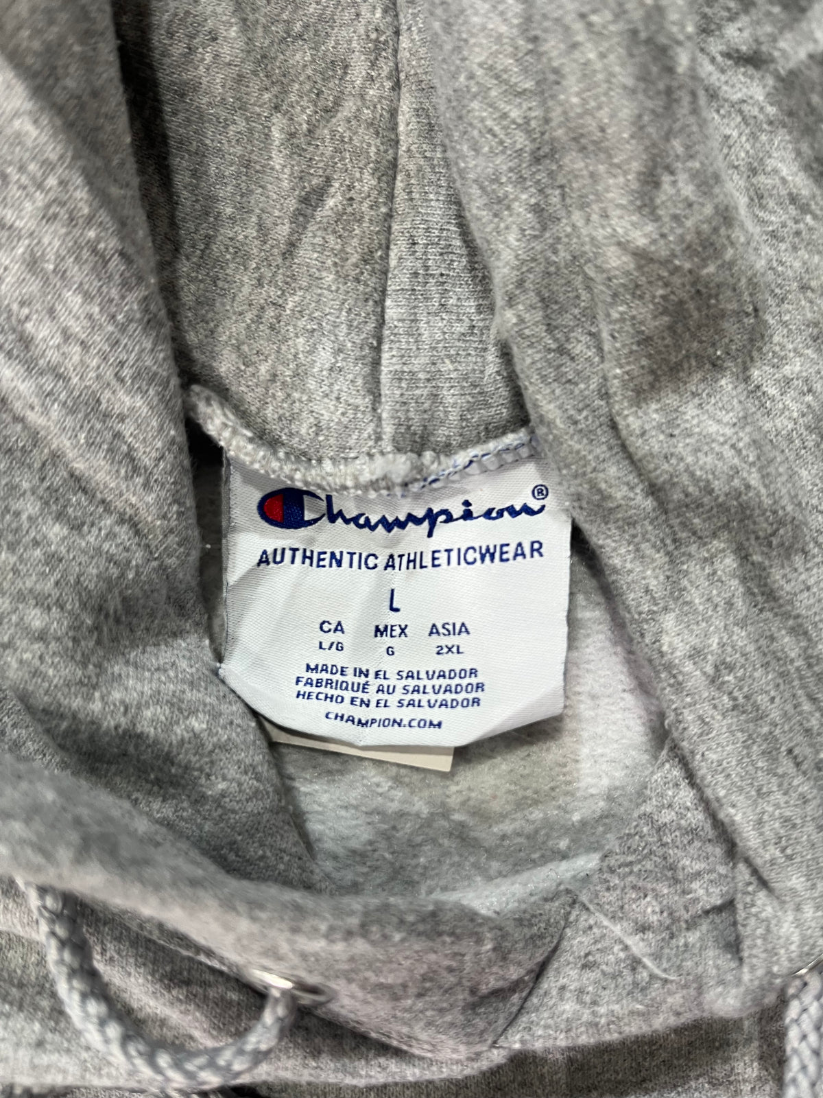 Close-up of a gray athletic hoodie interior label showing the Champion brand and size information.
