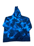 A blue and black tie-dye Champion hoodie is with hangers and other clothes visible in the background.