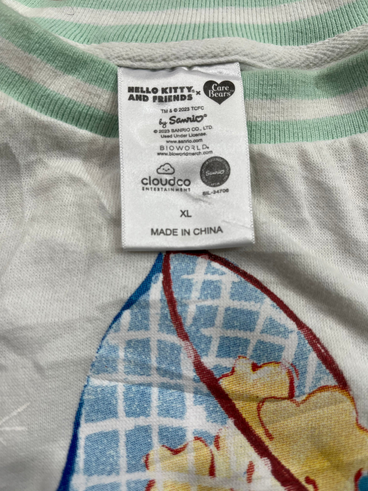 Close-up of a clothing size and care label sewn onto a Hello Kitty and Friends patterned garment, showing the brand name Samu' and size XL.