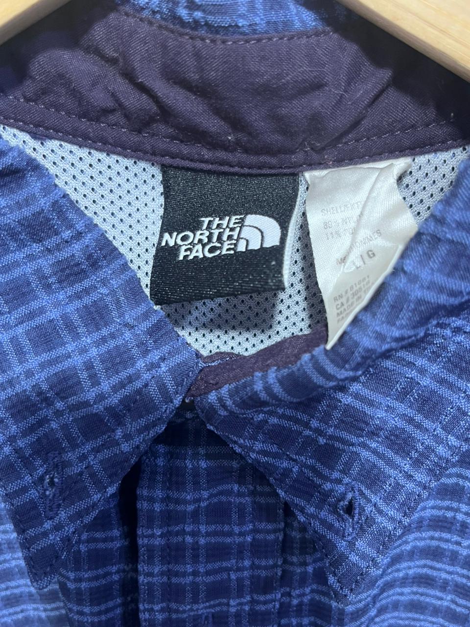 Close-up of a blue plaid shirt with The North Face logo tag.