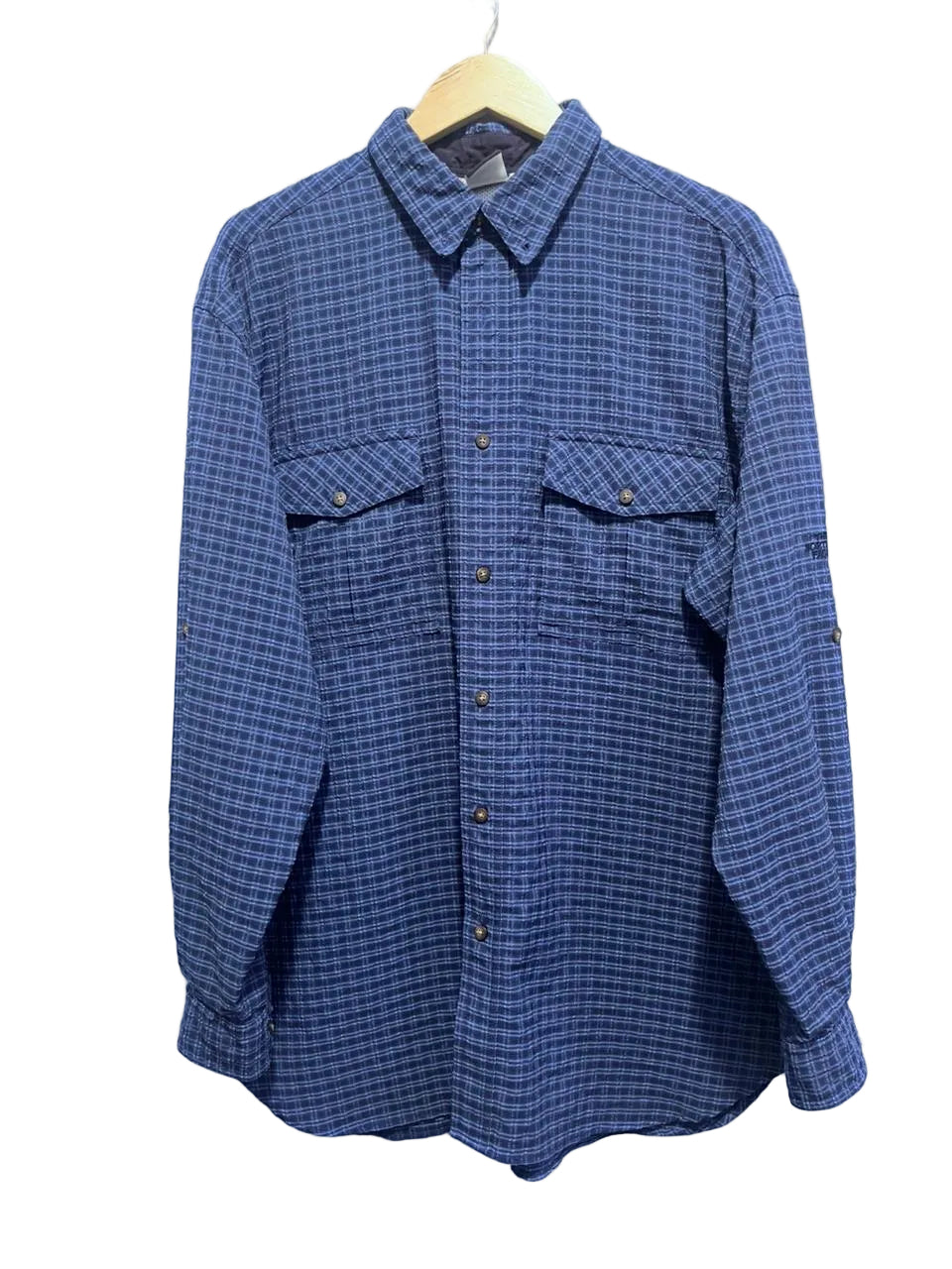 The north face blue plaid shirt on a hanger against a white wall