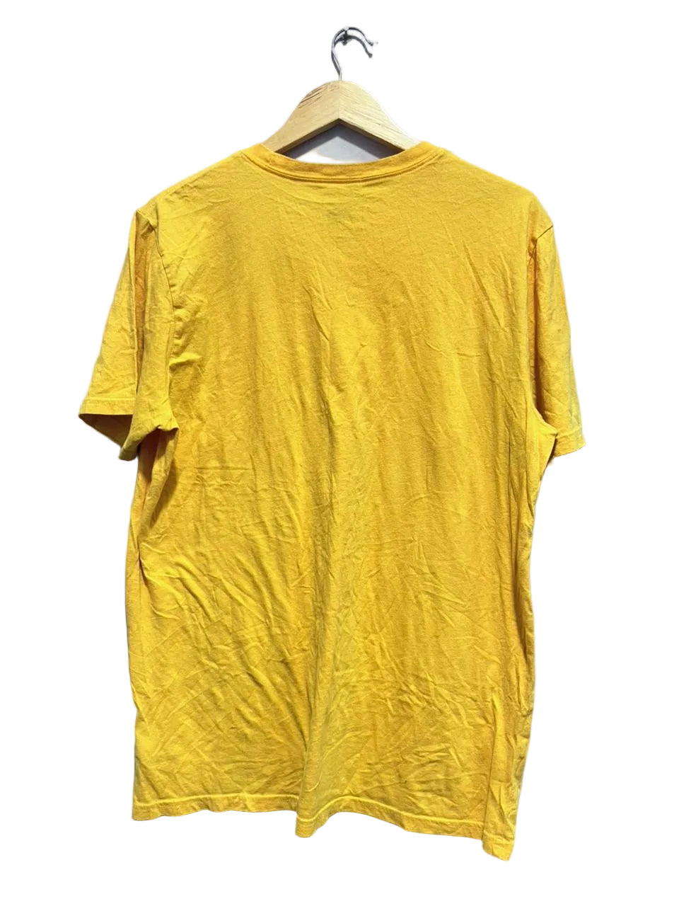 Yellow t-shirt on a hanger against a white wall