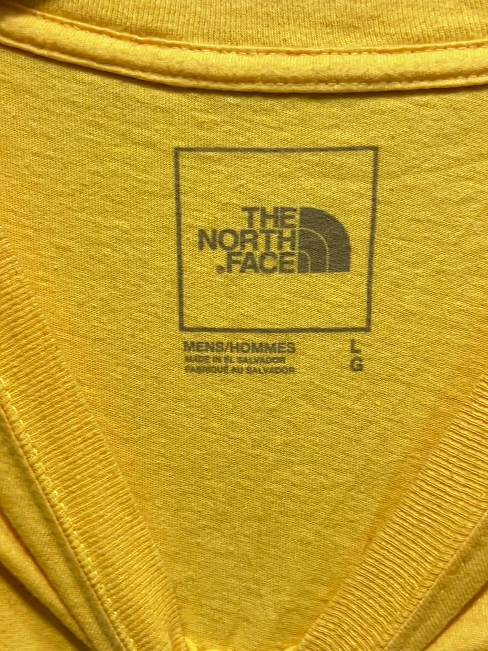 Close-up of a yellow t-shirt with The North Face logo.