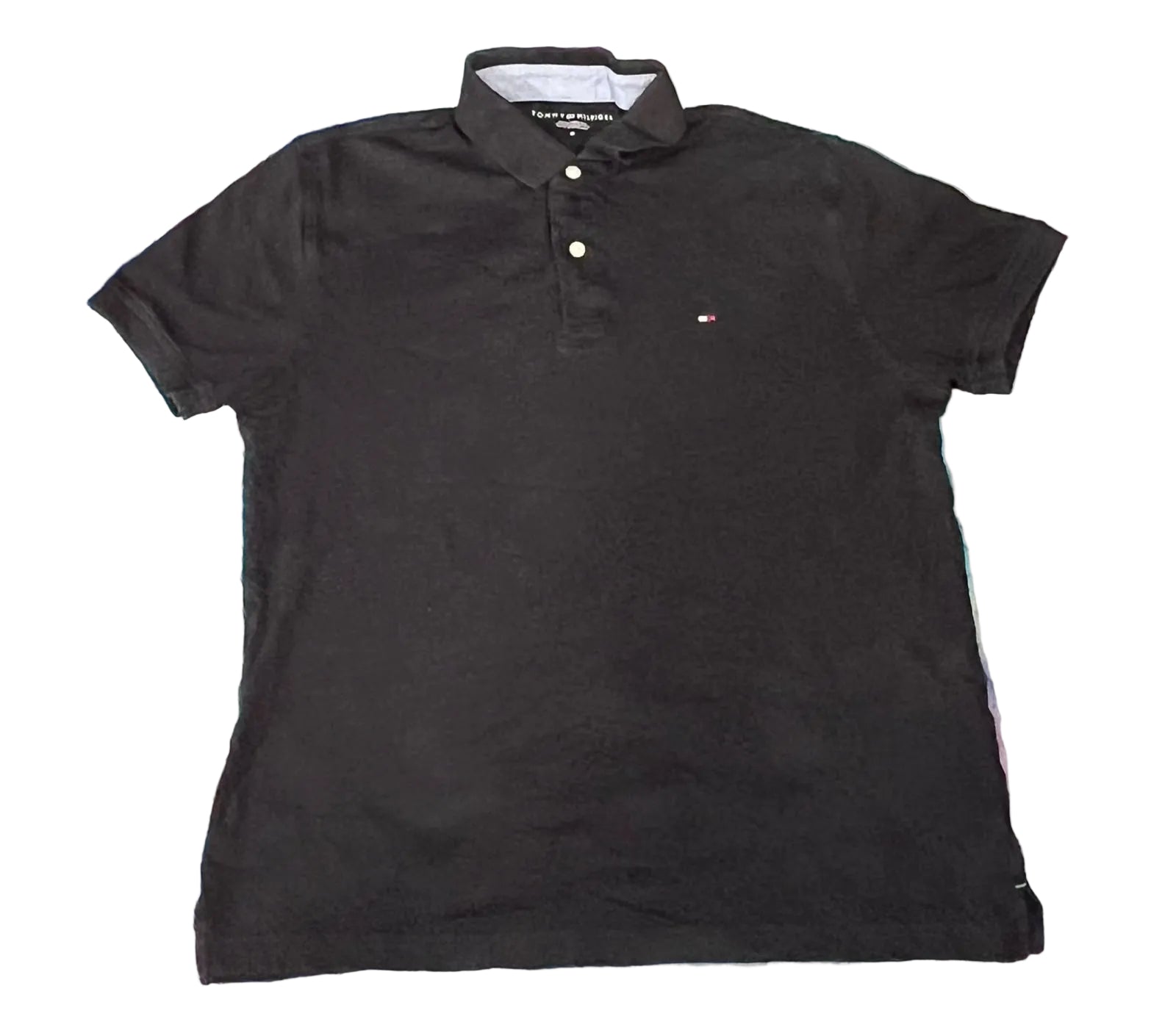 A black short-sleeve polo shirt by Tommy Hilfiger,. The shirt features a three-button placket and the signature embroidered Tommy Hilfiger flag logo on the left chest.