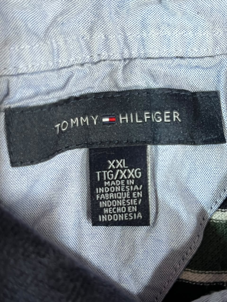 Close-up of a Tommy Hilfiger garment label showing the brand name on a black patch and size information for XXL.