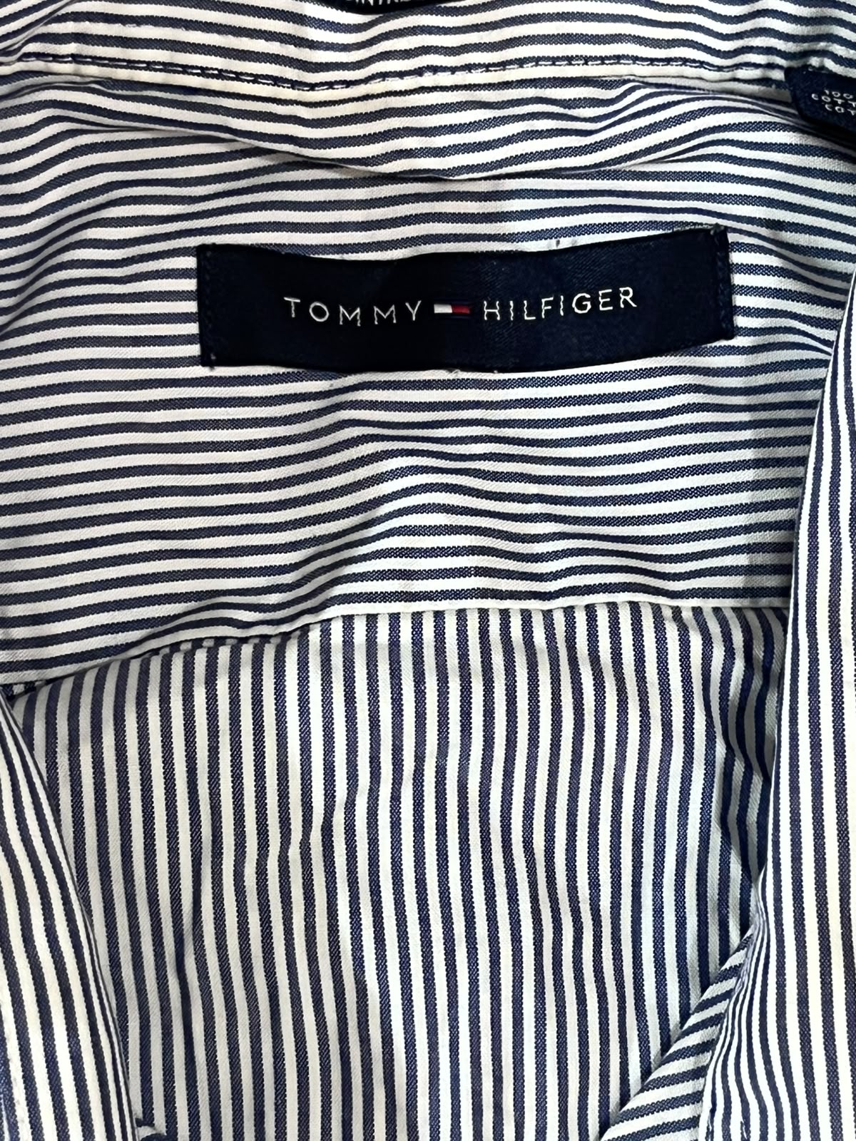 Close-up of a Tommy Hilfiger striped shirt lining with navy and white vertical pinstripes and a visible Tommy Hilfiger brand label.