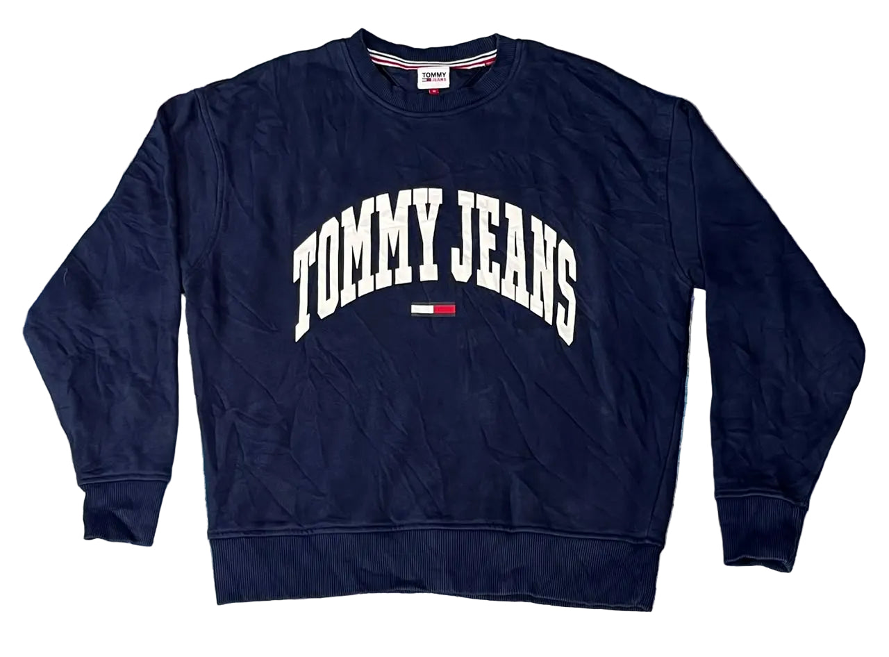 A navy blue crewneck sweatshirt with 'TOMMY JEANS' printed in white arched letters and a small red, white, and blue flag logo on the chest