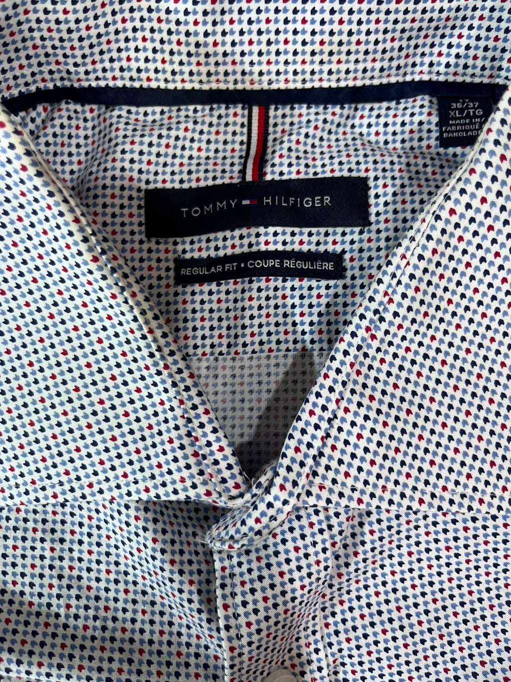 Close-up of a Tommy Hilfiger button-down shirt collar showing the brand label and a micro-checkered pattern of navy, red, and white dots.