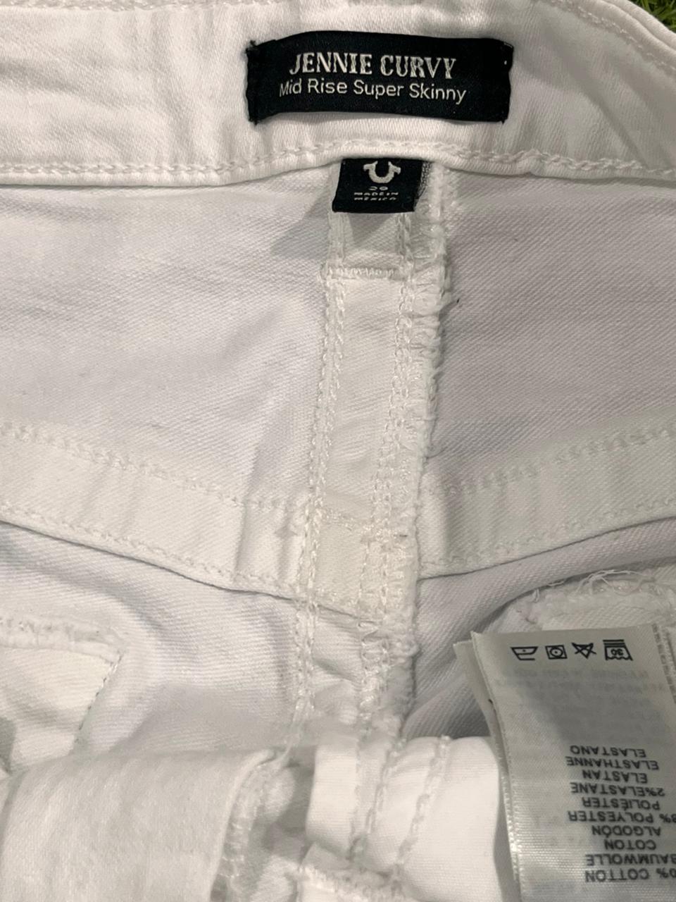 Close-up of white jeans with brand labels on a light background