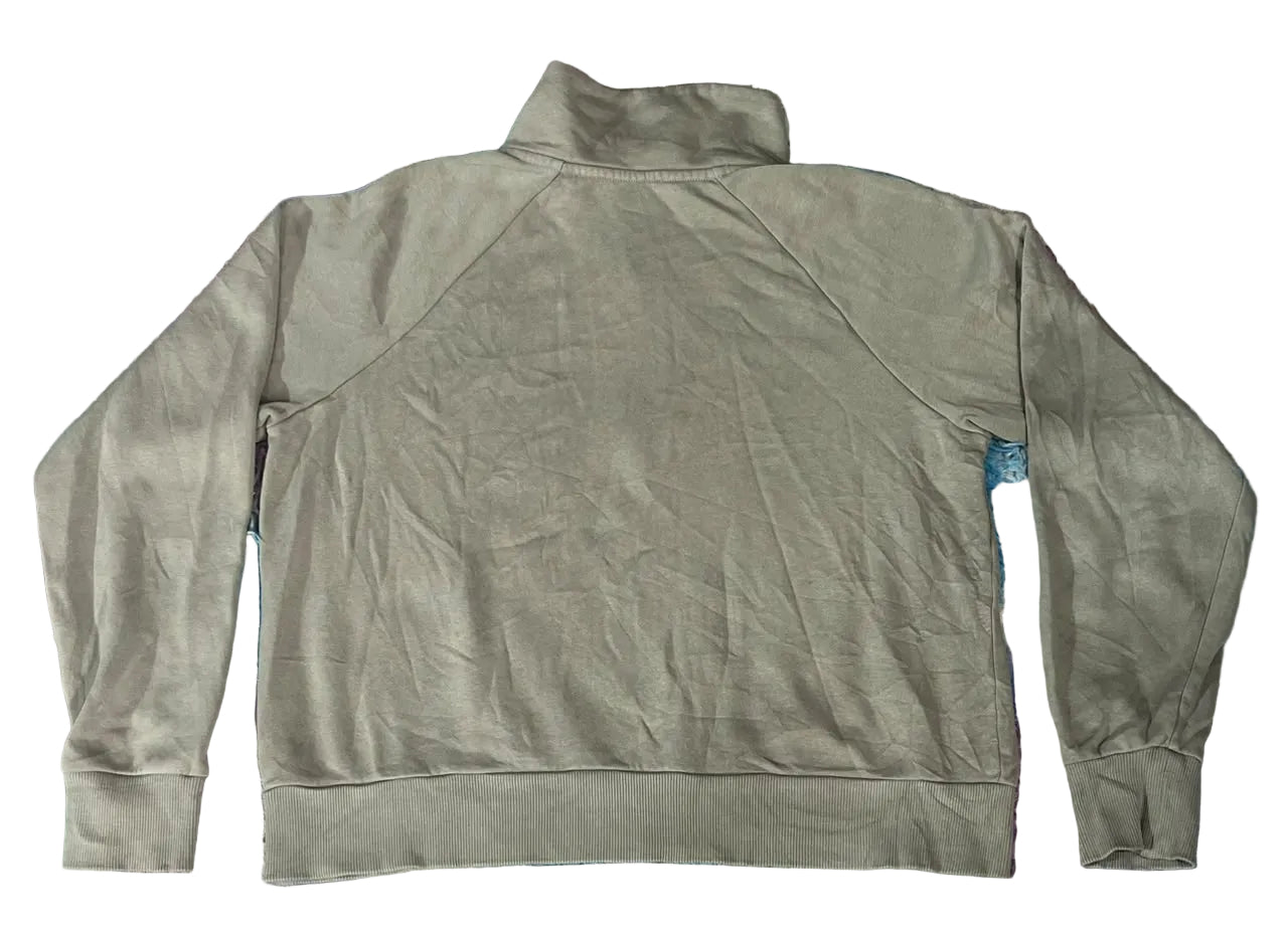 A sage green long-sleeve half-zip sweatshirt laid flat on a colorful, textured faux fur blanket.