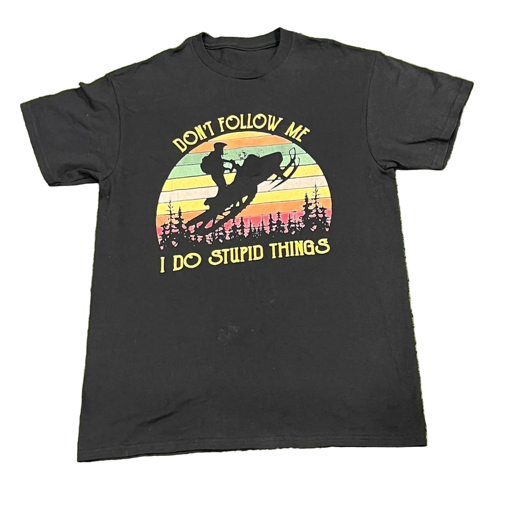 A black short-sleeve graphic t-shirt  The shirt features a retro-style circular sunset graphic with a snowmobile silhouette and the text 'DON'T FOLLOW ME' above and 'I DO STUPID THINGS' below in yellow.