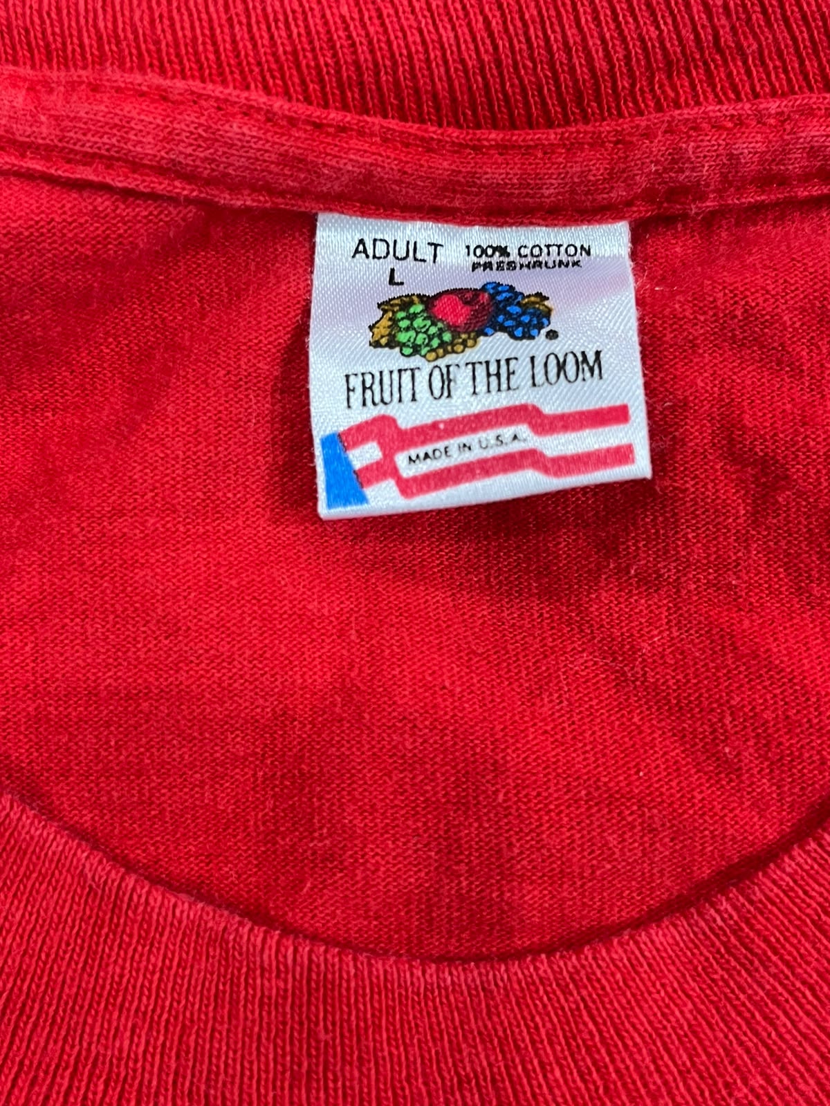 Close-up of a red cotton t-shirt neck label reading 'ADULT L FRUIT OF THE LOOM' with a colorful fruit graphic and 'MADE IN U.S.