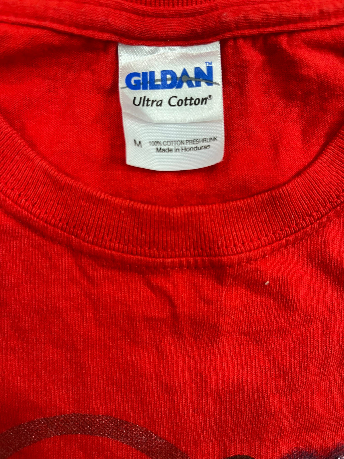 Close-up of a red cotton t-shirt showing the inner neck label which reads GILDAN Ultra Cotton.