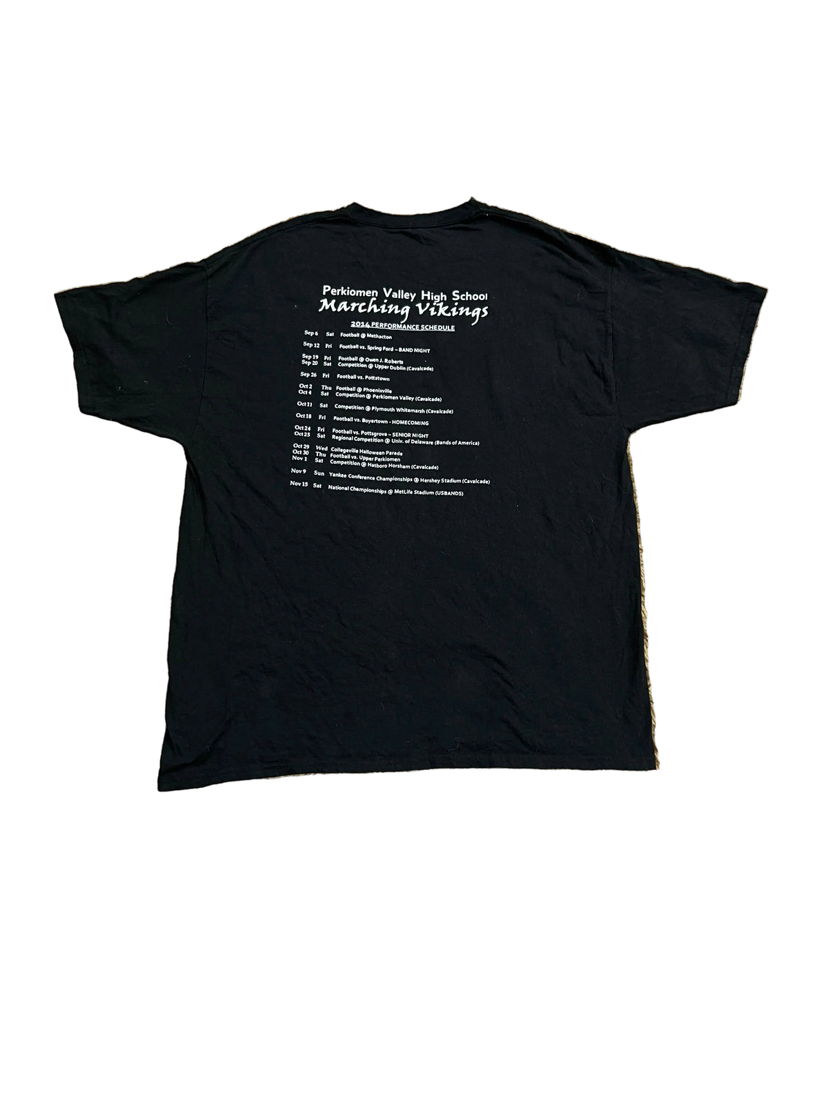 A black short-sleeve t-shirt ,owing the back side with white printed text that reads 'Pershing Vlei Wig Station Marching Vikings' and a list of locations and dates. Bare feet are visible at the bottom edge.